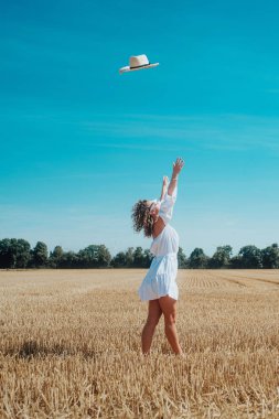 Beyaz elbiseli genç bir kadının portresi. Çayırda güneş gözlükleriyle poz veriyor.  