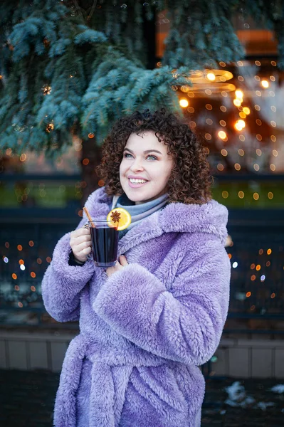 流行のバイオレットコートドリンクの巻き毛の女性は屋外で複数のワインを飲みます お祝いの背景 — ストック写真