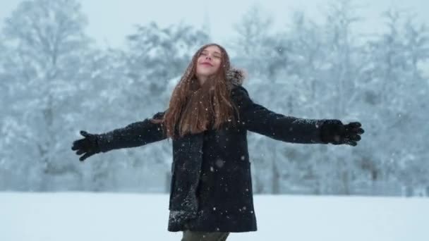 雪を楽しむ幸せな10代 女の子は雪の中で回転して雪をキャッチしている — ストック動画