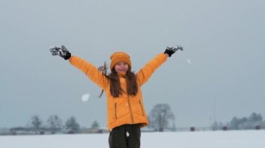 A happy teenager enjoying the snowfall. The girl is spinning in the snow and catching snow.