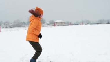 A happy teenager enjoying the snowfall. The girl is spinning in the snow and catching snow.