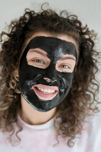 にきびの問題の皮膚を持つ若い美しい女性は 暗い化粧品マスクを適用し ホームケアの概念 — ストック写真