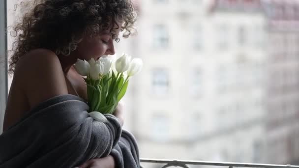 若い女性の美しい朝 春のチューリップの花束を開いて窓の上に座って スローモーション — ストック動画