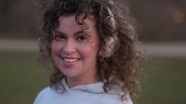 Genç, şık bir kadın kulaklıkla müzik dinliyor, şehirde dolaşıyor.