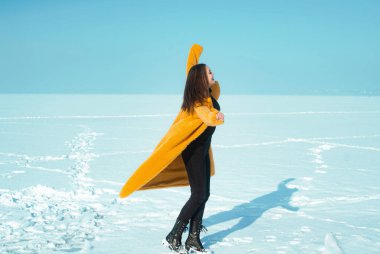 Sarı ceketli kadın karlı buzda eğleniyor, özgürlük konsepti.