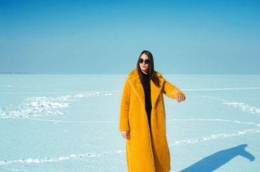 Sarı ceketli kadın karlı buzda eğleniyor, özgürlük konsepti.