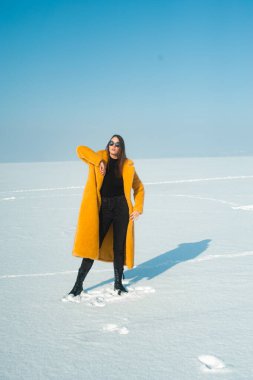 Sarı ceketli kadın karlı buzda eğleniyor, özgürlük konsepti.