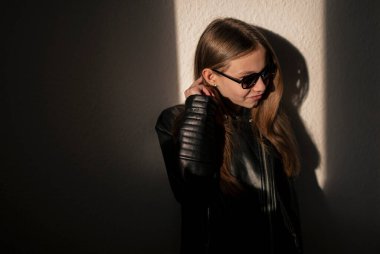 Gözlüklü, deri ceketli, gölgeli şık bir çocuk. 