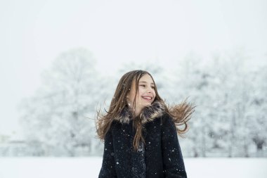 Küçük tatlı kız soğuk kış havasında karla eğleniyor. Kış mevsimi neşesi.