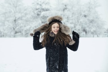 Küçük tatlı kız soğuk kış havasında karla eğleniyor. Kış mevsimi neşesi.