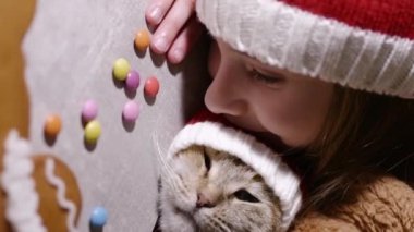  Noel Baba şapkalı çocuk Noel ağacı arka planında kış tatili için zencefilli ekmek yapıyor.