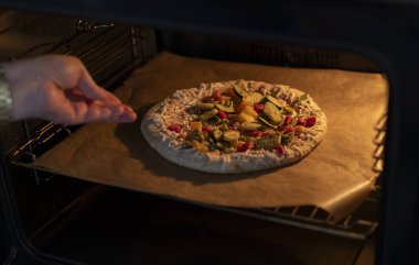 Kadın fırında lezzetli bir pizza pişirir.