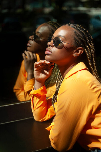 Young Woman Orange Shirt Braided Hair Stands Reflective Surface — Stock Photo, Image
