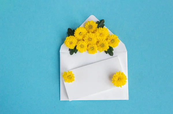 Envelope with flowers. Beautiful flowers in a mail envelope on a white background. greeting card for the holiday. Yellow-blue colors. copy space