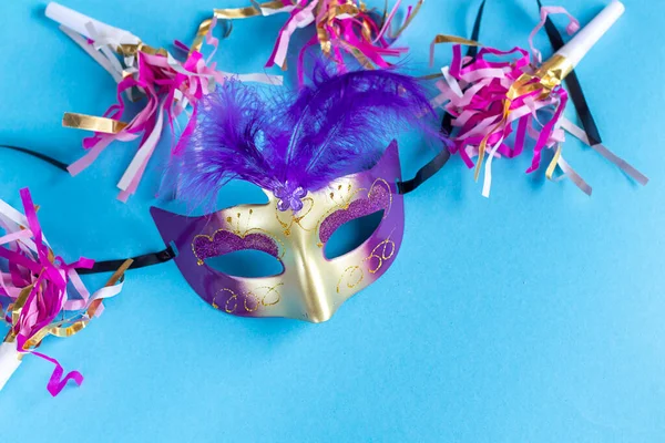 Festive face mask for carnival celebration on blue background. Mardi gras carnival background with carnival masks. Flat lay carnival concept.