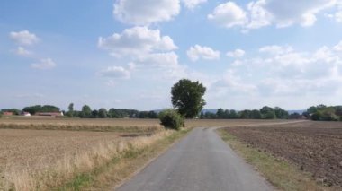 Road in the middle of the fields against the blue sky. 4K
