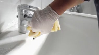 Bir kadın banyoda lavaboyu yıkıyor. Banyo temizliği