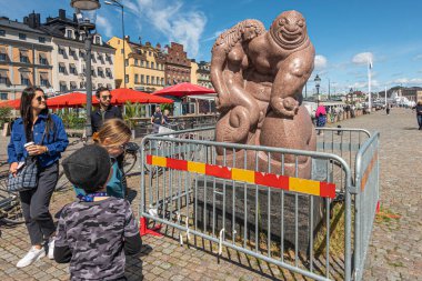 İsveç, Stockholm - 17 Temmuz 2022 Skeppsbron rıhtımında çitlerle korunan Çevre Partisi mermer heykeli üzerinde mavi gökyüzüne karşı kollarında uyuyan erkek karakter ve kadın.