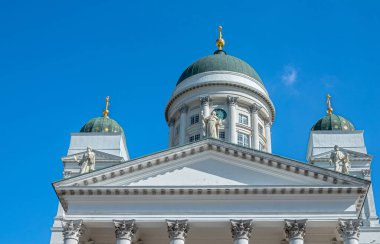 Helsinki, Finlandiya - 19 Temmuz 2022: Mavi gökyüzüne karşı altın tepeli 3 kubbeli beyaz katedralin pedikürü. Soldan sağa 3 Havari heykeli: Bartholomew, John, Matthew, 