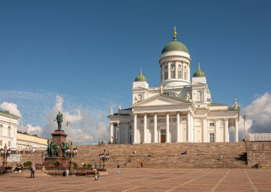 Helsinki, Finlandiya - 19 Temmuz 2022: Rusya Çarı II. Alexander 'ın Senato Meydanı' ndaki heykeli, diğer heykellerin kombinasyonlarıyla birlikte mavi bulutların altındaki beyaz katedralin yanında yer almaktadır.