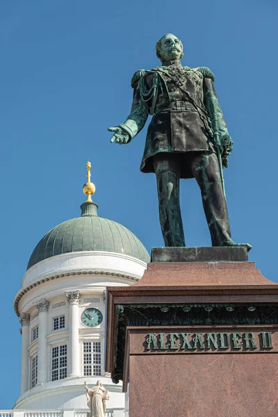 ヘルシンキ フィンランド 2022年7月19日 ロシアのツァル アレクサンダー2世像が上院広場に閉鎖され 白い大聖堂が青空の下に隠れています 緑がかったブロンズ像 — ストック写真
