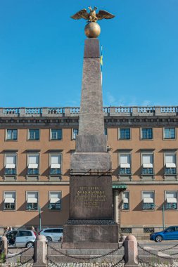 Helsinki, Finlandiya - 19 Temmuz 2022: Mavi gökyüzüne karşı üzerinde çift başlı kartal bulunan Tsarina 'nın Taş Anıt Anıtı' nın kapatılması. Şehir manzarası ve trafik arkaplan olarak