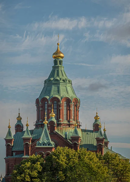 芬兰赫尔辛基 2022年7月19日 俄罗斯东正教Uspending Ski主教座堂的红砖和绿色屋顶高耸在蓝天下的绿树之上 每座塔的顶部都是金色的 — 图库照片