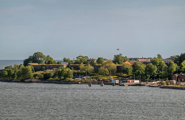 芬兰赫尔辛基 2022年7月20日 Suomenlinna Fortress从海上出发 绿树成荫 草木丛生 短码头与结合处的集装箱和机器 都在浅蓝色的天空下灰水 — 图库照片