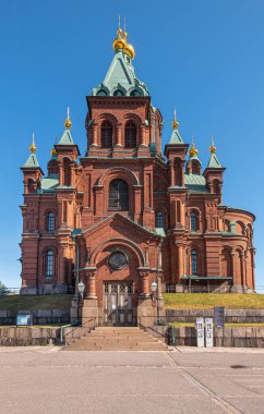 Helsinki, Finlandiya - 20 Temmuz 2022: Uspenski Katedrali. Güney kırmızı tuğlalı cephe birden fazla kuleye sahip hepsi mavi gökyüzüne karşı altın tepeyle kaplı, park yerinden görüldüğü gibi.. 