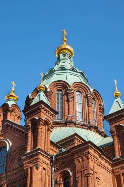 Helsinki, Finlandiya - 20 Temmuz 2022: Uspenski Katedrali. Mavi gökyüzüne karşı üzerinde altın haç olan kırmızı tuğla ve yeşil kubbe ana kulesine yakın çekim. 3 küçük kule dahil