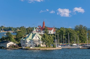 Helsinki, Finlandiya - 19 Temmuz 2022: Valkosaari adasındaki Ravintola NLK 'nın çatısı yeşildi. Adasındaki Saaristo Restoranı 'nın mavi bulutların altında kırmızı çatısı vardır. Limanda yatlar 