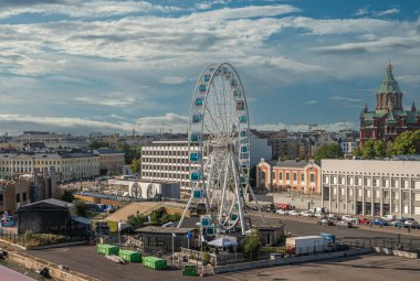 Helsinki, Finlandiya - 20 Temmuz 2022: Tarihi liman. Skywheel ve Uspenski Katedrali 'nin kırmızı tuğla duvarları ve mavi bulutların altında yeşil kubbeleri var. Yakınlarda Uçan Sinema ile Şehir Manzarası