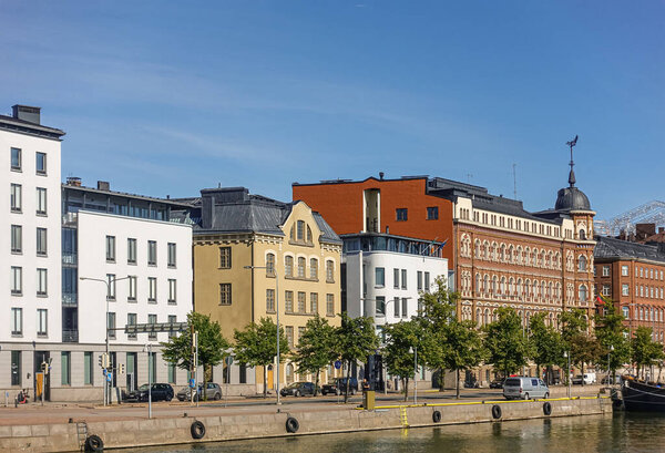 Helsinki, Finland - July 20, 2022: Pohjoissatama Harbor. Facades on west side with Lithuania Embassy and other buildings, one historic with corner lookout tower under blue sky