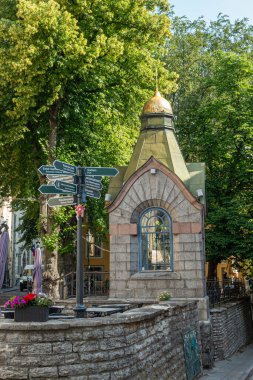 Estonya, Tallinn - 21 Temmuz 2022: Altın tepeli Tikk ve Olievimagi caddeleri yeşil yaprakların altında birleşen tarihi küçük şapel. Oturma alanındaki karmaşık yönlü oklar