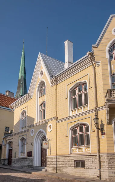 エストニア タリン 2022年7月21日 エストニア児童文学センター黄色の正面玄関と青空の下のメインエントランス 後ろに聖オラフ緑の尖塔 ピック73のストリートシーン — ストック写真