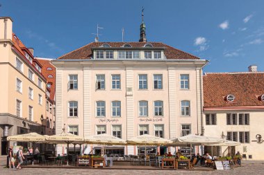 Estonya, Tallinn - 21 Temmuz 2022: Açık renkli cephe, Mad Murphy 's Pub and Grill North Town Hall Square' in doğu yakasında. Kutsal Ruh, mavi gökyüzünde gökyüzüne doğru yükseliyor. Terastaki insanlar.