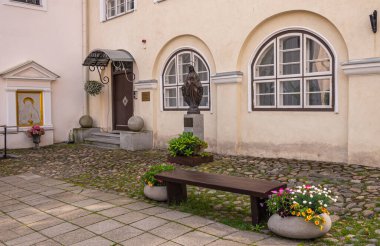 Estonya, Tallinn - 21 Temmuz 2022: St. Peter ve St. Paul Katedrali. Bakire Meryem bronz heykeli ve altın çerçeveli Paul duvar resmi olan bir avlu. Çiçekler renk ekler