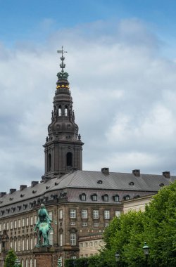 Kopenhag, Danimarka - 23 Temmuz 2022: Atı üzerindeki Absalon, mavi bulutlar altında gri taş Christiansborg Sarayı ve Kraliyet sembollerine bakmaktadır. Yeşil yaprak