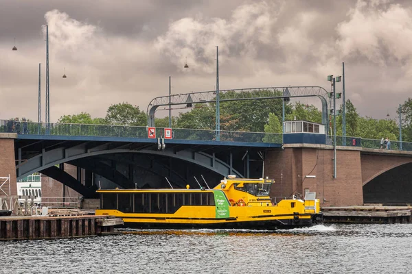 丹麦哥本哈根 2022年7月23日 黑黄轮渡船Pas80在灰蒙蒙的云彩下在兰格布罗大桥下行驶 一些绿叶和交通标志增加了色彩 — 图库照片