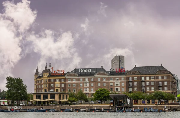 丹麦哥本哈根 2022年7月23日 位于兰格布罗 Langebro 和布赖吉岛 Islands Brygge 一角的大型棕色石头建筑建筑群 在灰色云彩景观下容纳了许多企业 港湾水面上的汽艇 — 图库照片