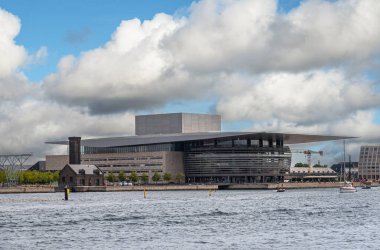 Kopenhag, Danimarka - 24 Temmuz 2022: Opera Binası veya Operaen modern binası tarihi Pompalama İstasyonu ile yoğun mavi bulutların altında, liman suyu önünde