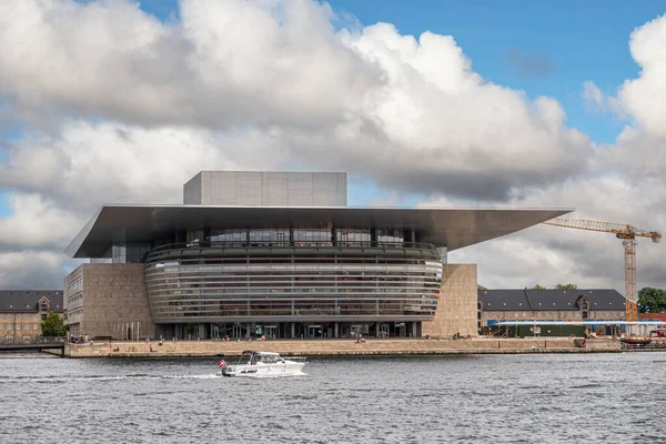 丹麦哥本哈根 2022年7月24日 在浓密的蓝云景观下的歌剧院或现代运行机制的正面景观 前面有船的港湾水 侧面有建筑用起重机 — 图库照片