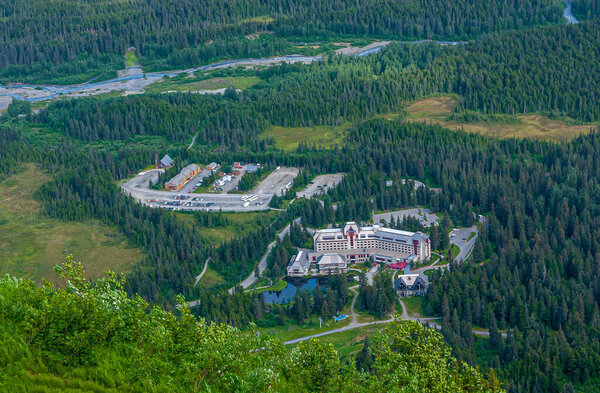 Girdwood Alaska, USA - July 23, 2011: Alyeska Resort buildings and terrian set in green forested valley, seen from up the mountain. Blue Glacier Creek water cuts through