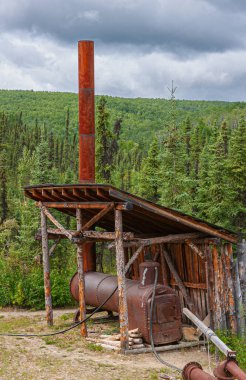 Fox, Alaska, ABD - 26 Temmuz 2011: Eldorado Altın Madeni Müzesi ve Park. Uzun bacalı, antika kırmızı buhar makinesi, hepsi metal, çatıda yeşil bir kadın ve bulutların altında.