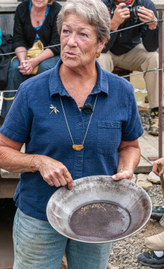 Fox, Alaska, ABD - 26 Temmuz 2011: Eldorado Altın Madeni Müzesi ve Park. Kot pantolonlu ve mavi gömlekli kadın tavasını altın tozu parçacıklarıyla gösteriyor.