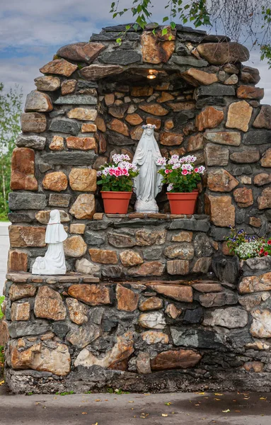 stock image Fairbanks, Alaska, USA - July 27, 2011: Lourdes-style grotto at Immaculate Conception Catholic Cathedral. Closeup show Mary and Bernadette as white only statues. Some flowers