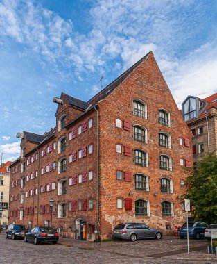 Kopenhag, Danimarka - 13 Eylül 2010: Mavi bulutlar altında Nyhavn Otel 'in tarihi kırmızı tuğlalı çok katlı yakın çekimi. Önde arabalar, yeşil yapraklar..