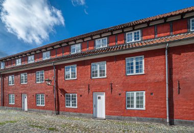 Kopenhag, Danimarka - 13 Eylül 2010: Kastellet 'teki kırmızı tuğla binalar, kaleler ve kaleler, mavi bulutların altında. Gra kaldırım taşları arasında yeşil otlar