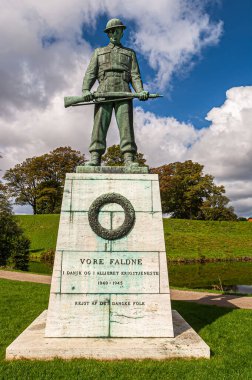 Kopenhag, Danimarka - 13 Eylül 2010: Vore Faltne yeşil bronz heykeli, Kastellet 'in önündeki kireç taşı kaidesinin önünde, kalenin önünde, mavi bulutların altında yeşil surlar altında.