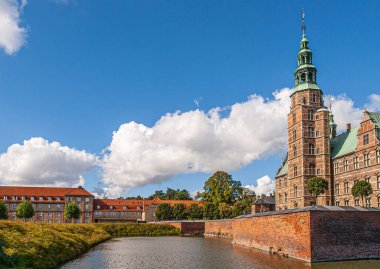 Kopenhag, Danimarka - 13 Eylül 2010: Peyzaj, SW bakış açısı, baskın kulesi ve mavi bulutlar altında surları olan kırmızı tuğla Rosenborg Yuvası 'nın üzerindeki hendeği gösteriyor. Ufuktaki kırmızı çatılar